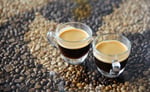 Two Ristretto coffee cups standing on floor of coffee beans